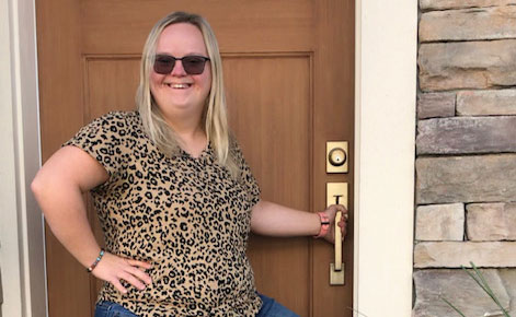 Woman with Down syndrome at the doorway to her home