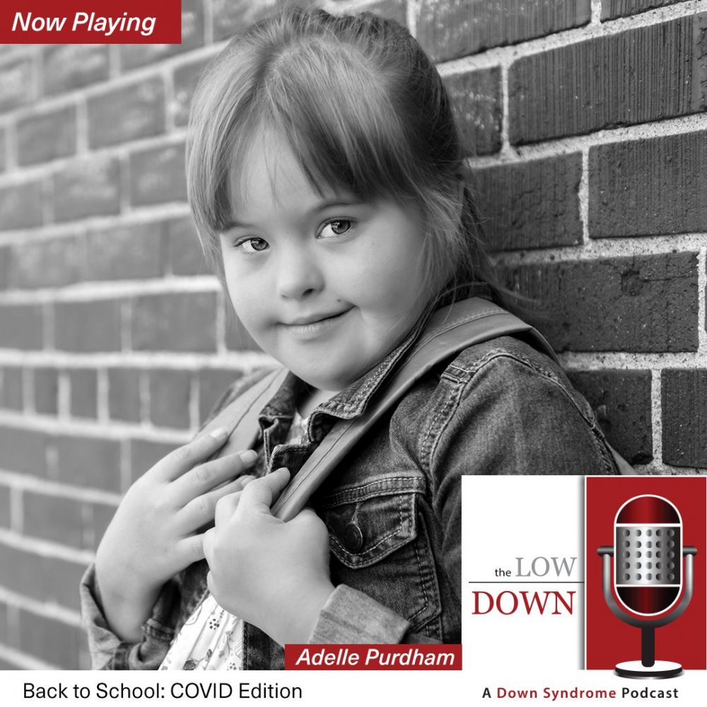 Girl with Down syndrome wearing backpack leaning against brick wall