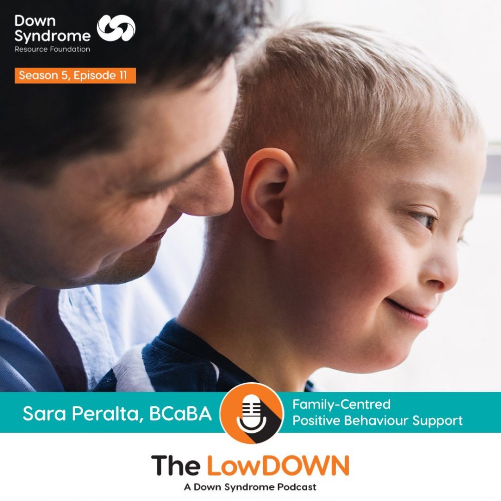 Father looks over the shoulder of boy with Down syndrome sitting in his lap