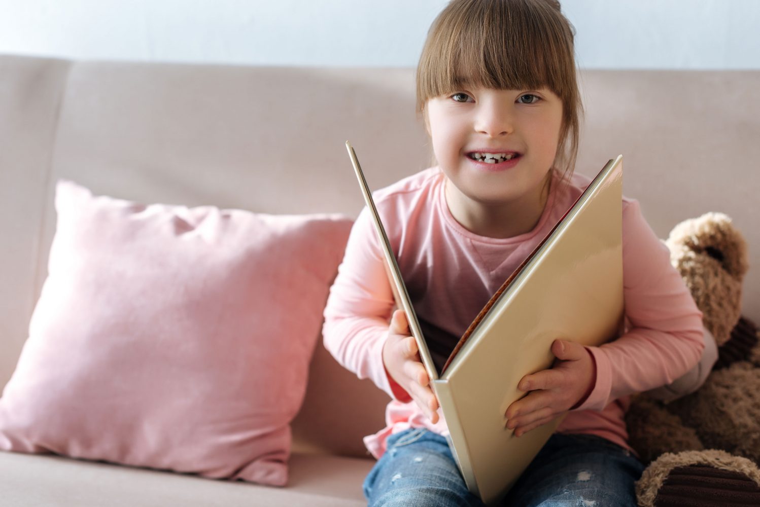 Girl with Down syndrome reads book on couch