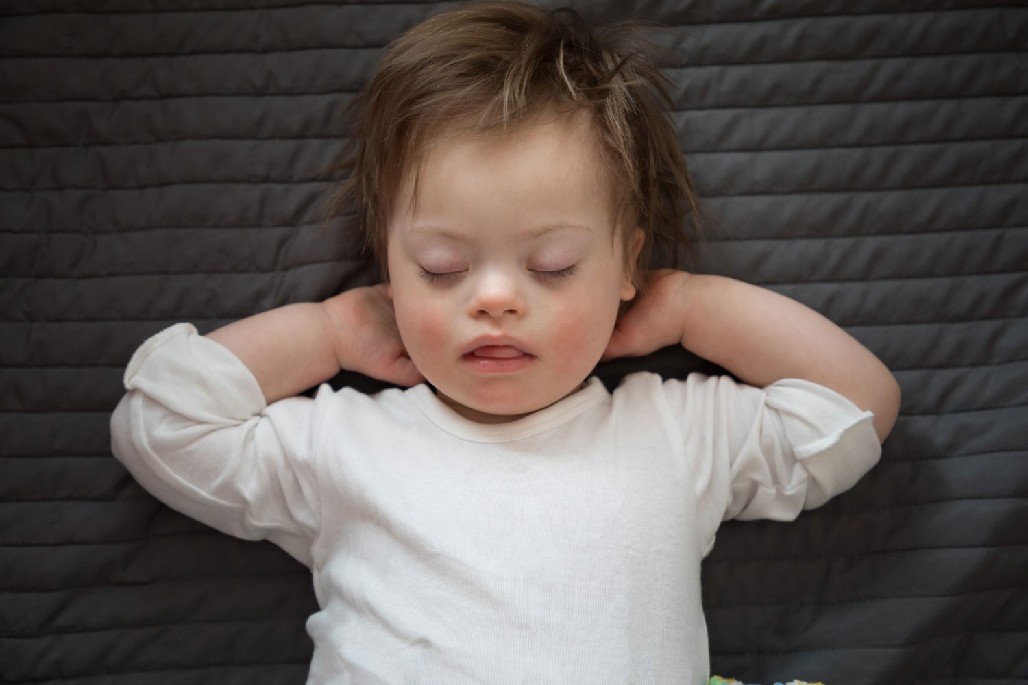 Toddler with Down syndrome sleeping on bed