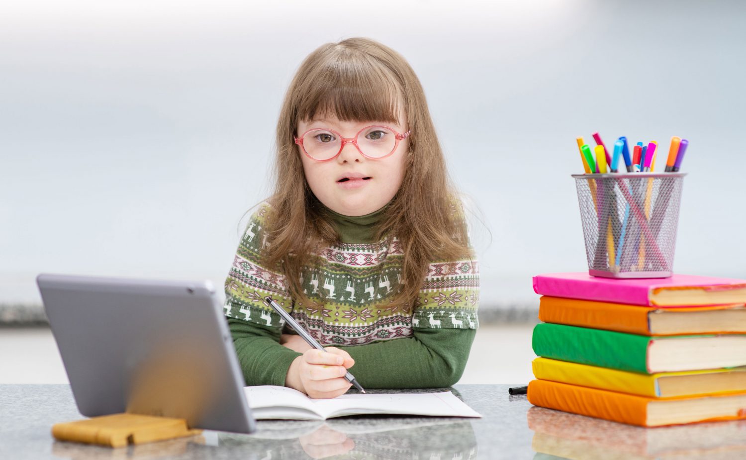 Young girl with Down syndrome does school work with tablet