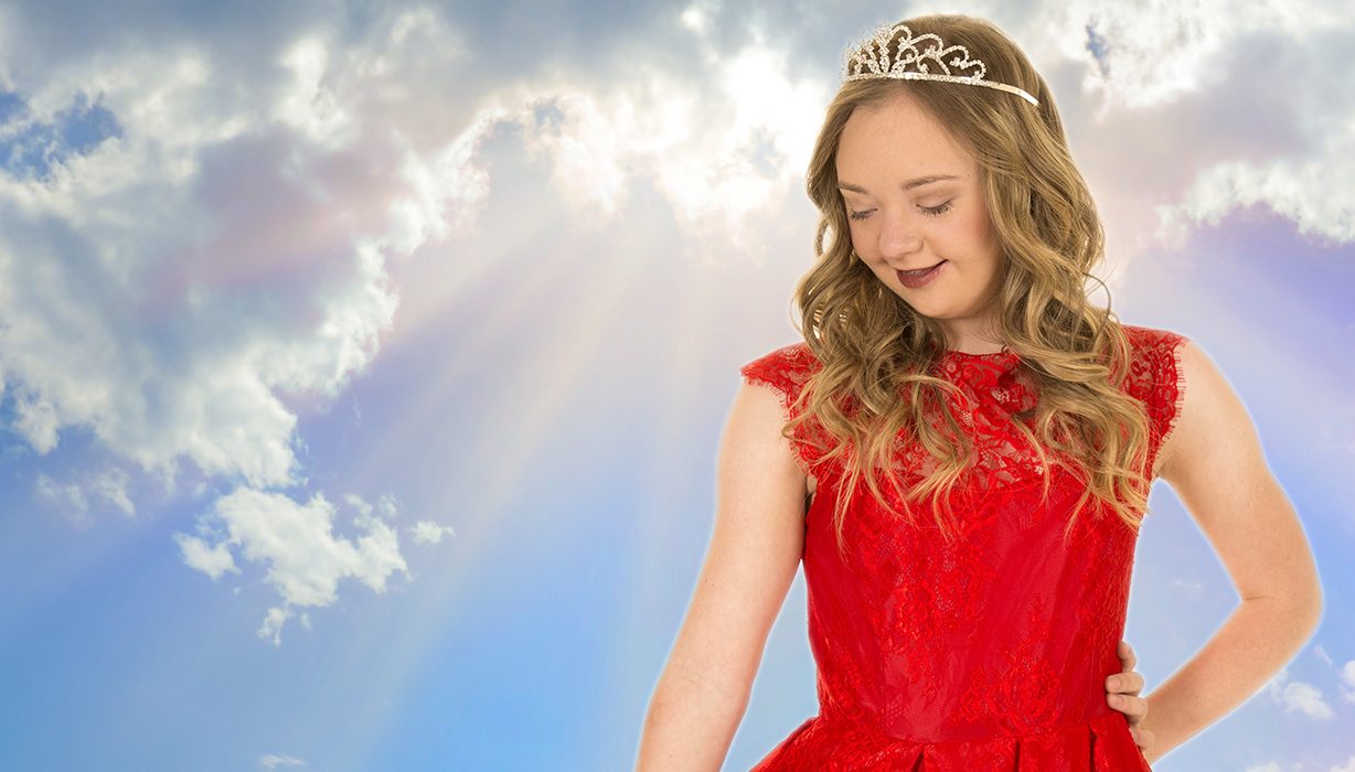 Teenage girl with Down syndrome dressed like a princess in front of sun beams