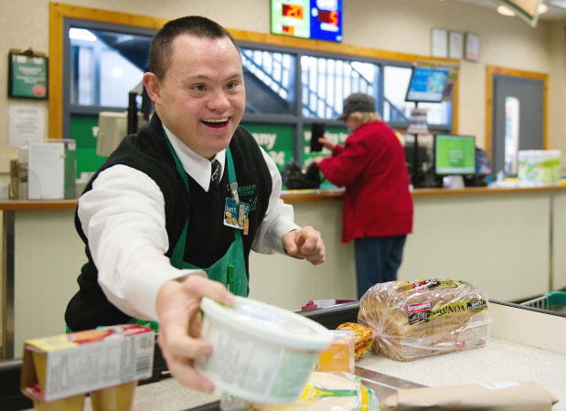 Man with Down syndrome packs groceries for customer
