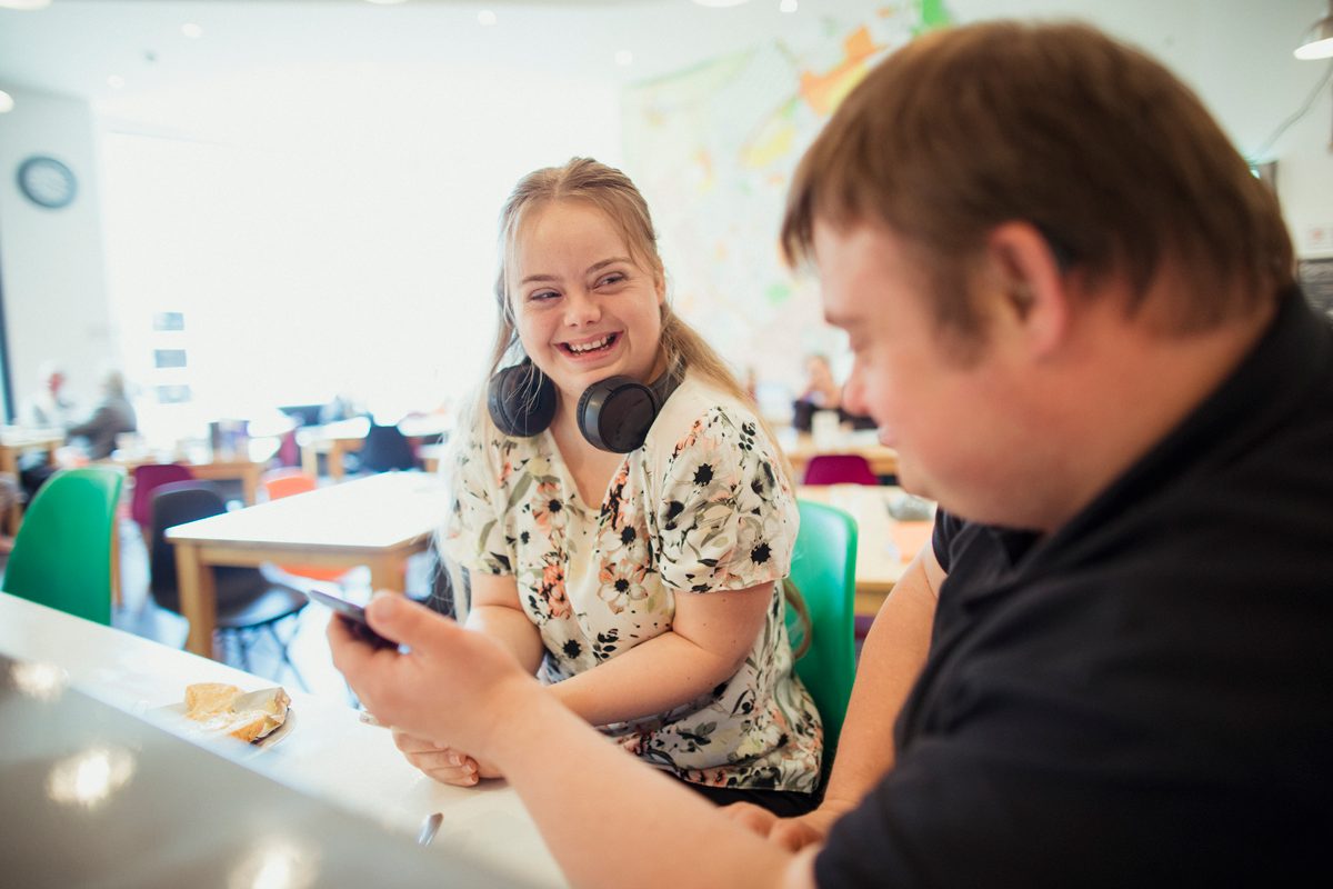 Young woman and man, both with Down syndrome, talk in classroom