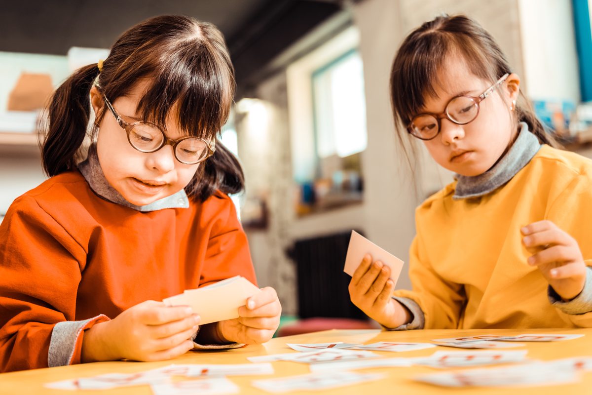 Two sisters with Down syndrome sort picture cards on table