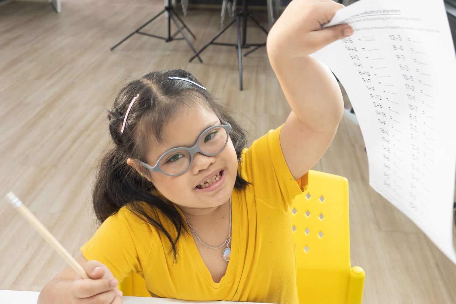Girl with Down syndrome proudly holds up her math worksheet