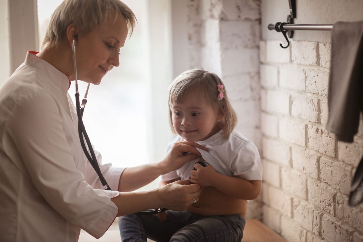 Doctor examines young girl with Down syndrome with a stethescope