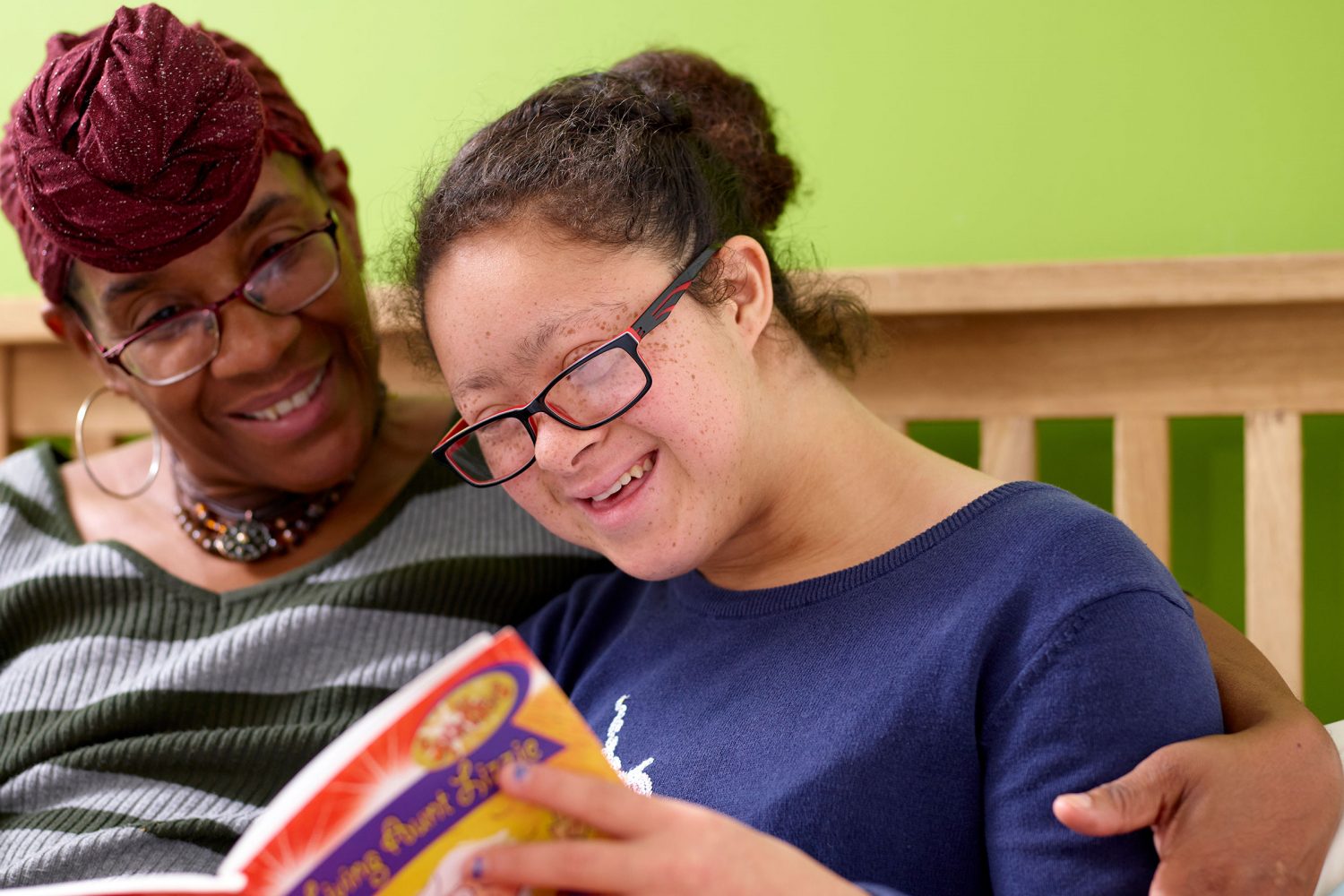 Teenage girl with Down syndrome reads book with teacher