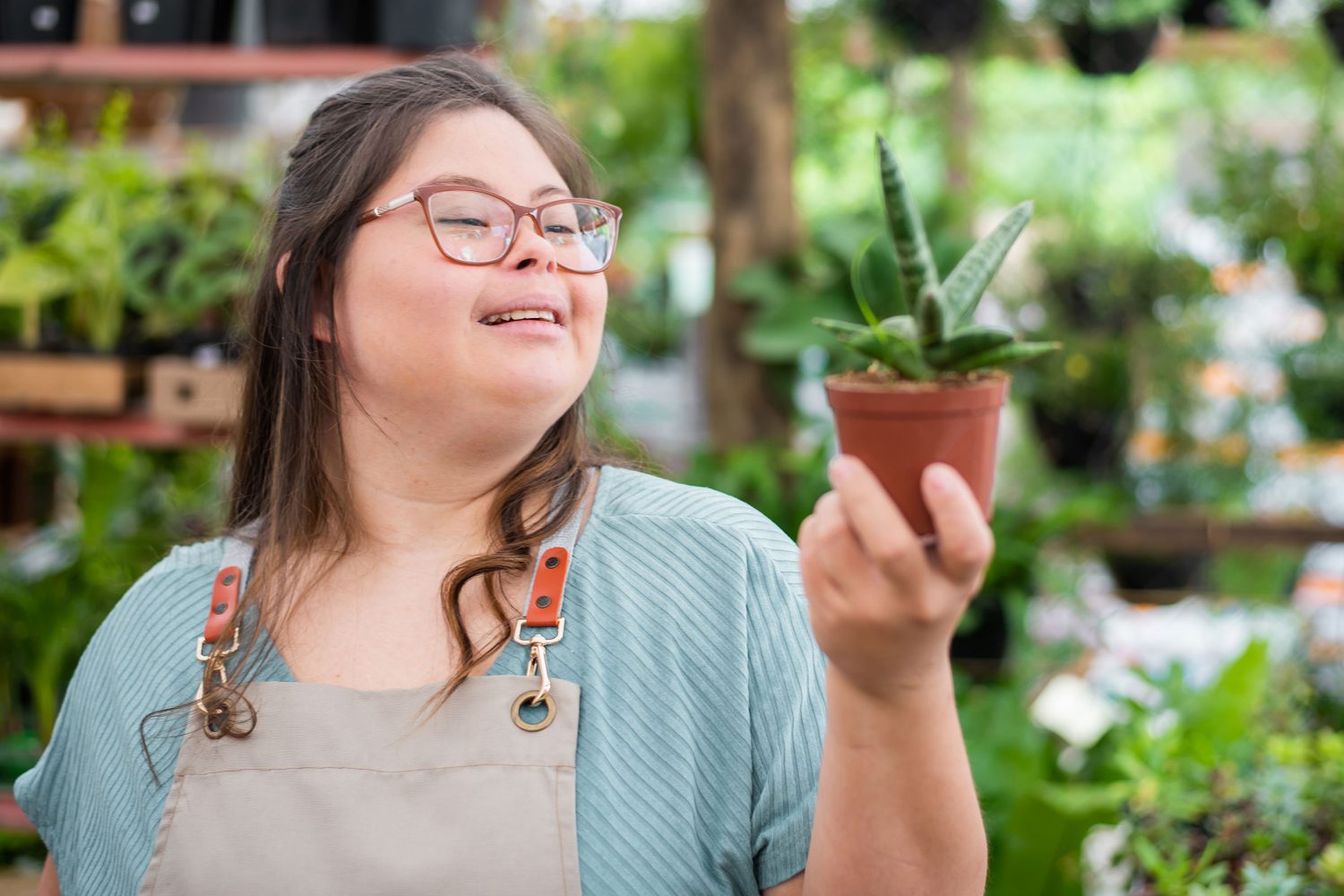 Girl with Down syndrome holds plant in garden center