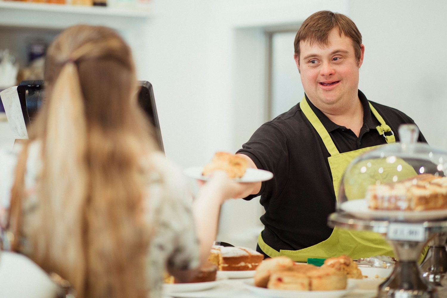 Man with Down syndrome serves customer at cafe