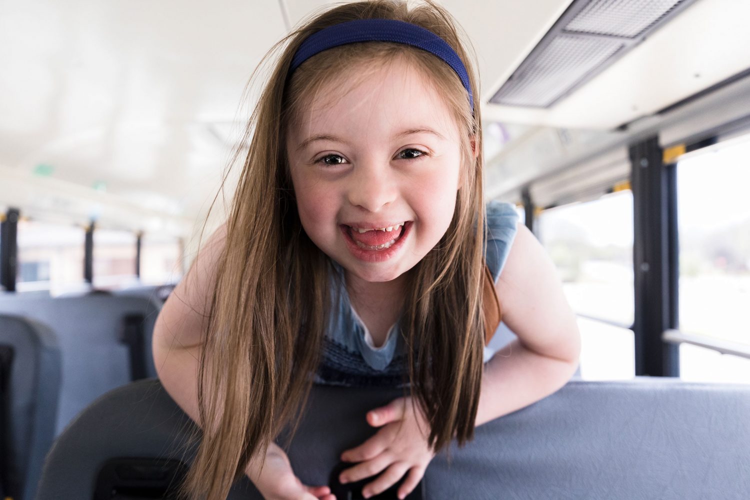 Girl with Down syndrome smiles on school bus
