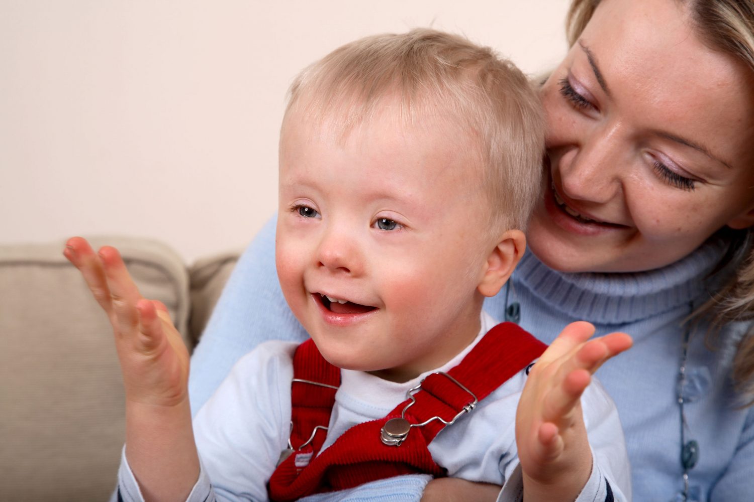 Young boy with Down syndrome clapping on mom's lap