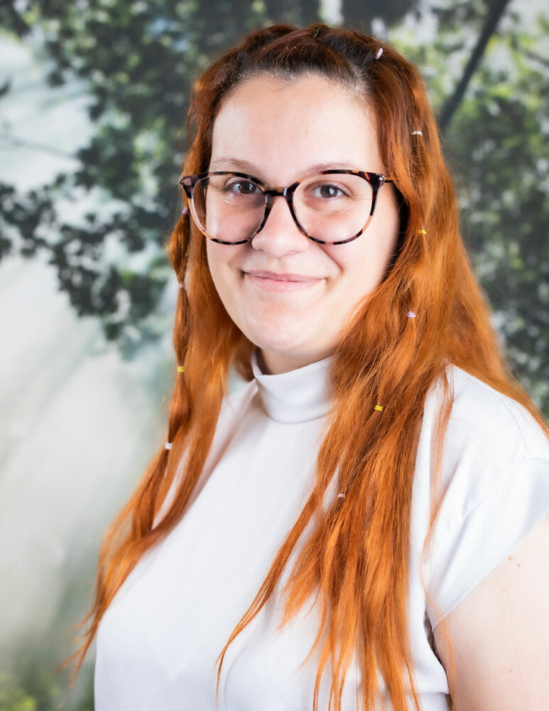 headshot of woman with red hair, white top and glasses