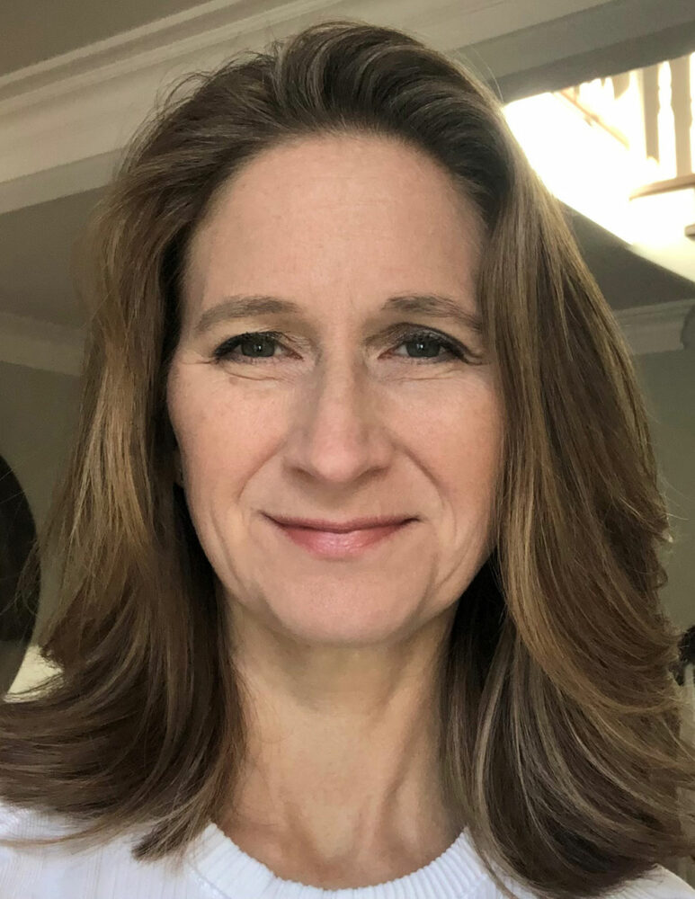 headshot of woman with brown hair and white top