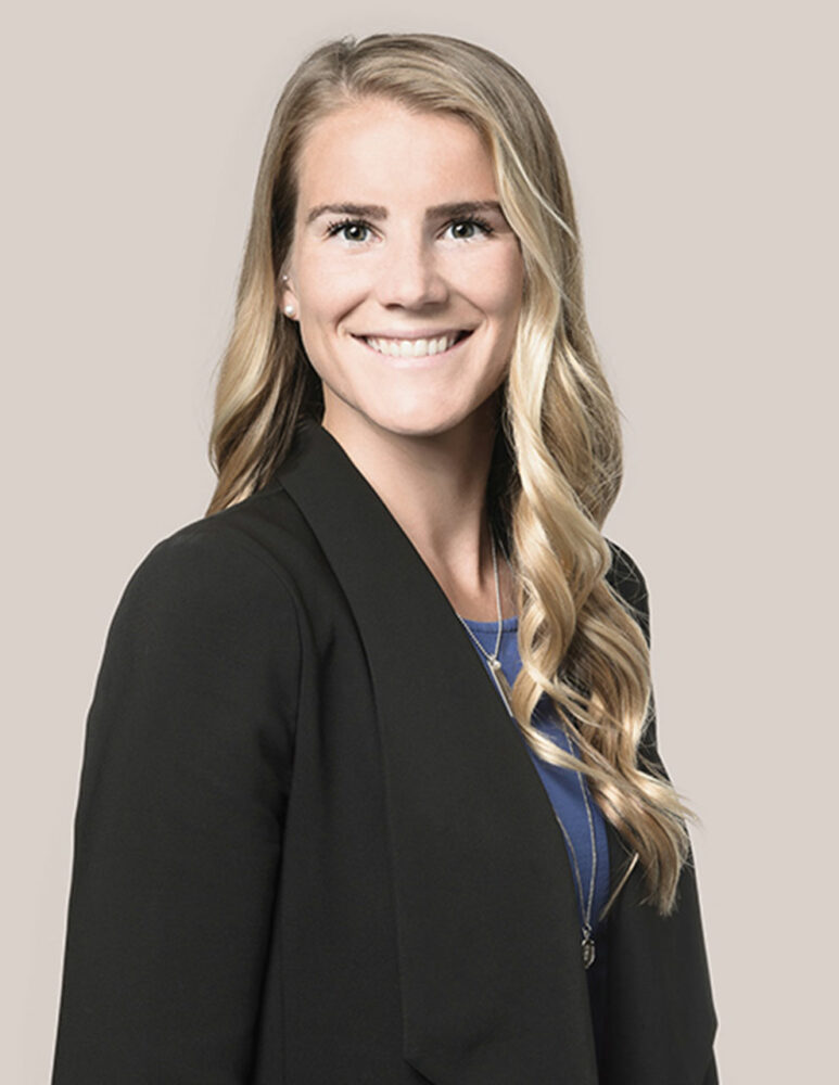 headshot of blonde haired woman in blue top and black jacket