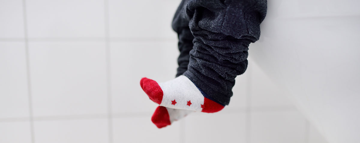 young child's feet dangling from toilet