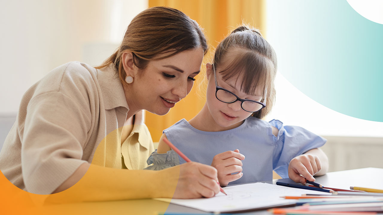 Asian teacher assists caucasian girl with Down syndrome with writing on paper