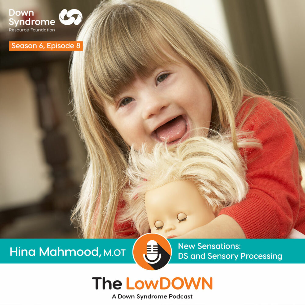 white female toddler with Down syndrome laughs and hugs doll