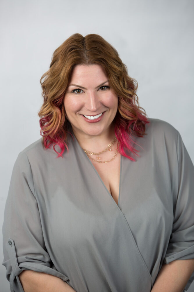 white woman with brown and pink hair and grey shirt (headshot)