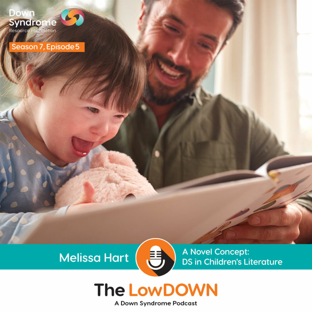 female toddler with Down syndrome laughs while reading book with dad