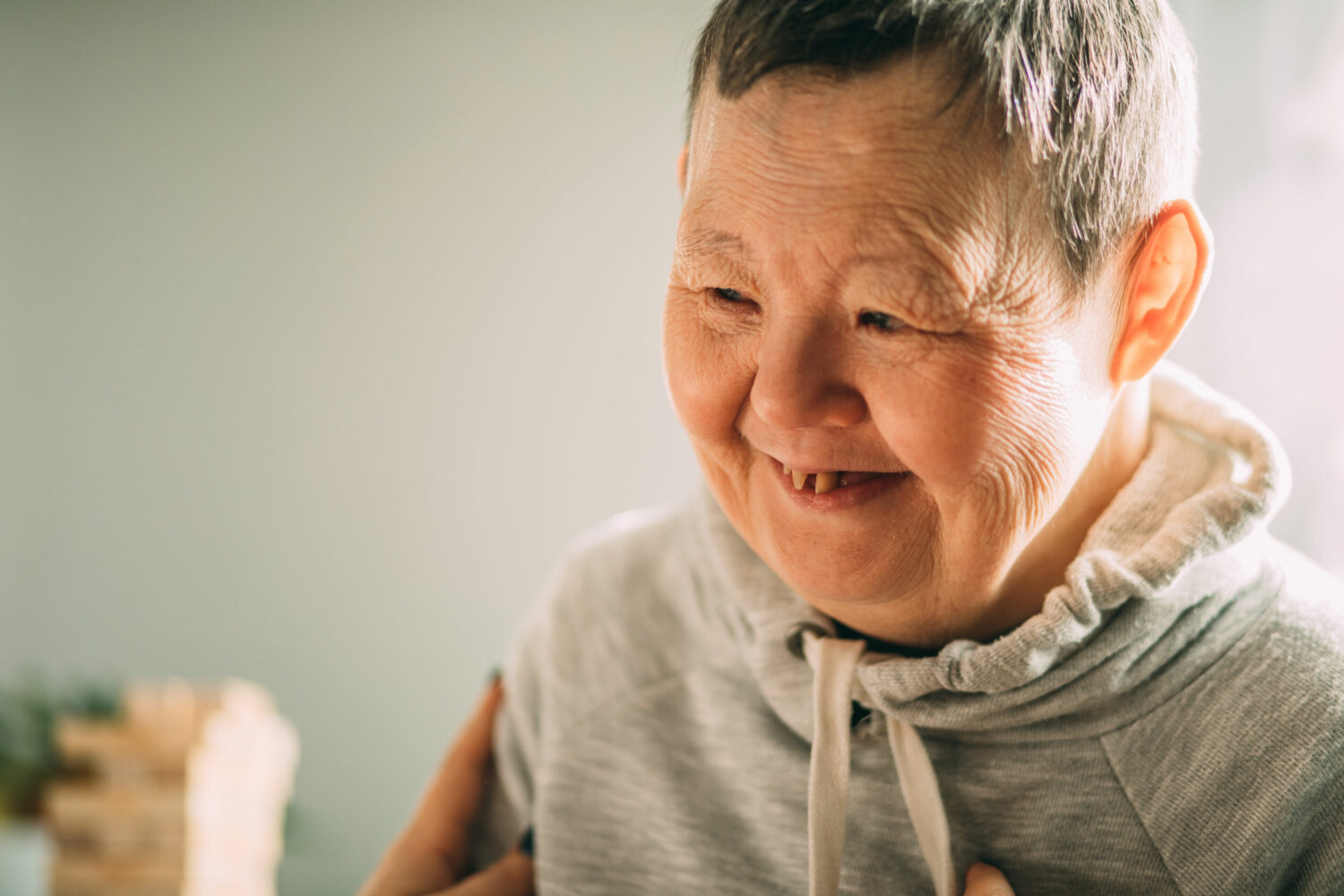 smiling old white woman with Down syndrome, with short gray hair and a gray hoodie