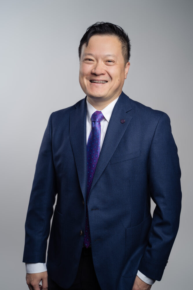 Asian business man with black hair, navy suit, white shirt and purple tie