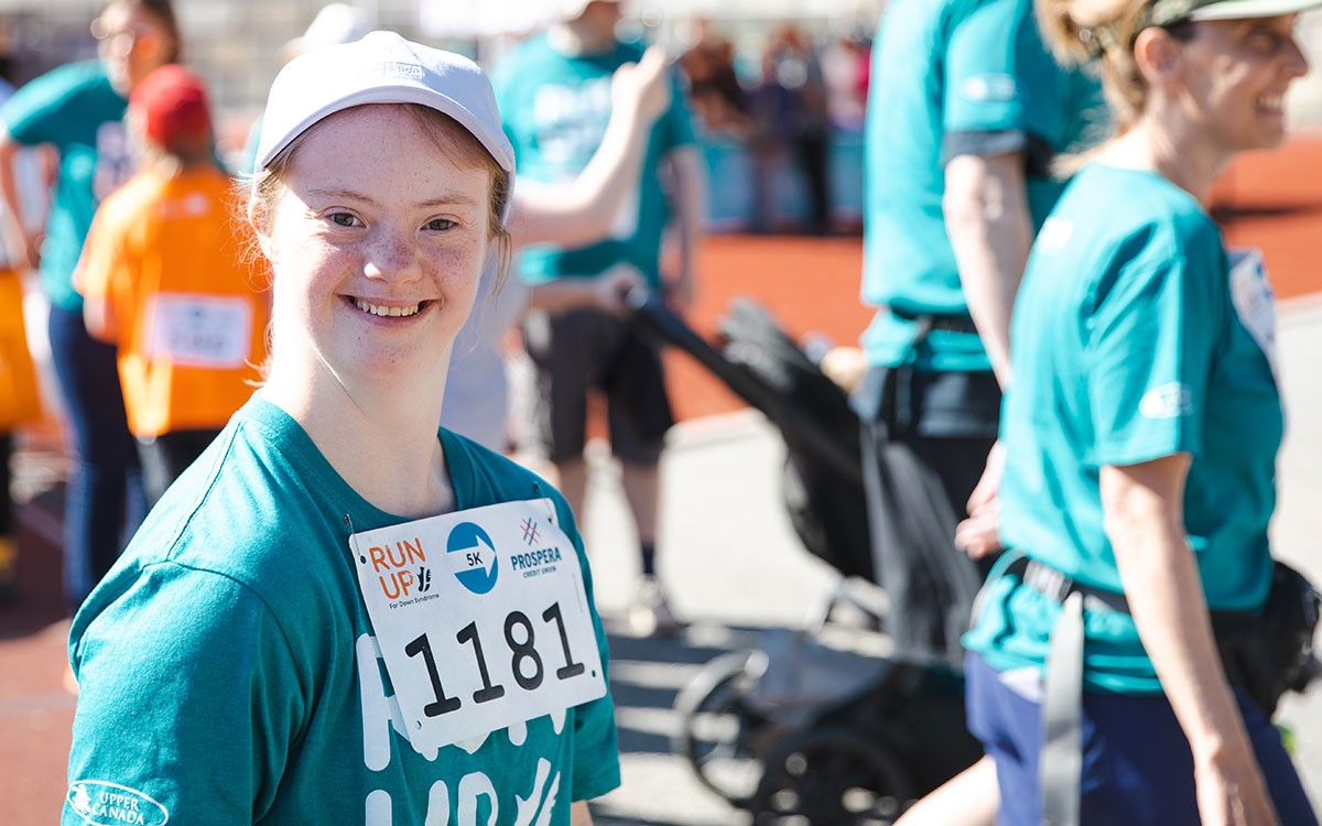 young white woman with Down syndrome wearing turquoise shirt and runner bib