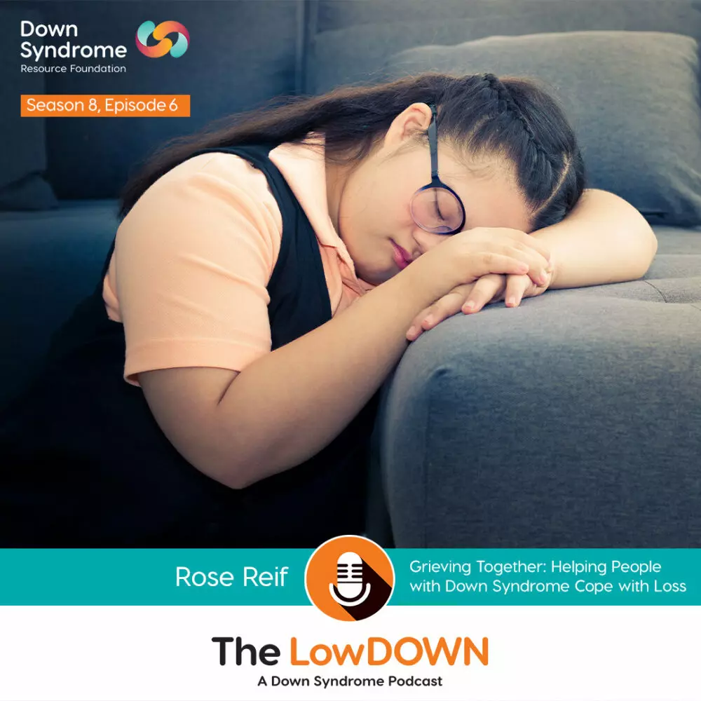 young asian woman with Down syndrome, wearing black, laying with her head in her hands in sadness
