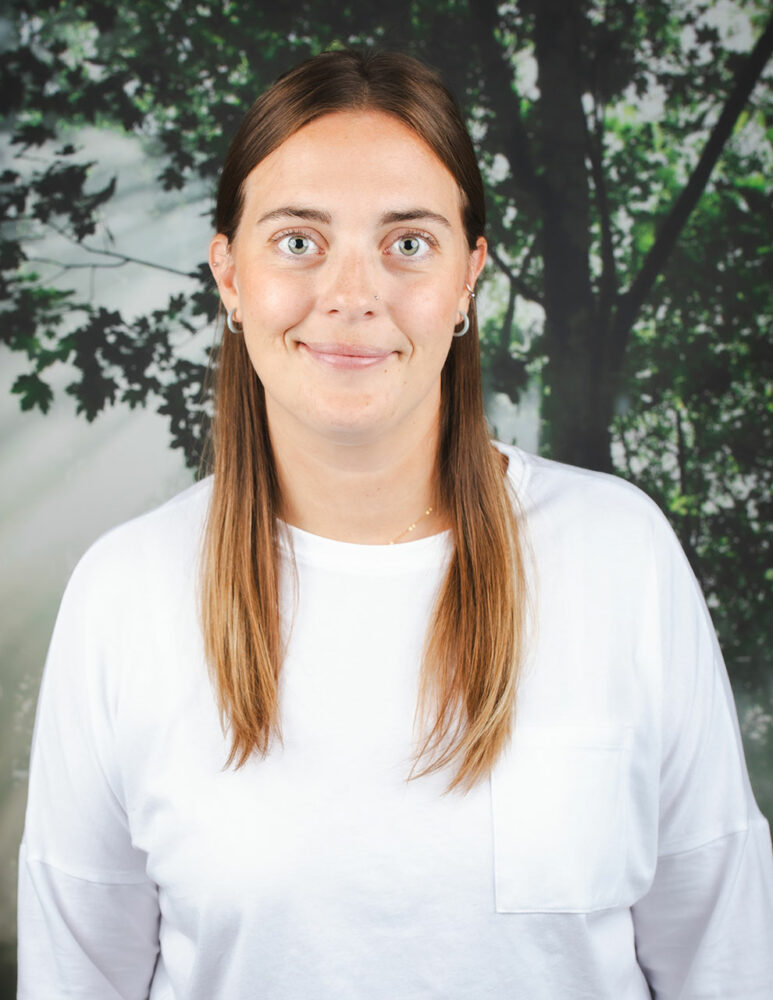 smiling white woman with long light brown hair wearing white long-sleeve shirt (headshot)