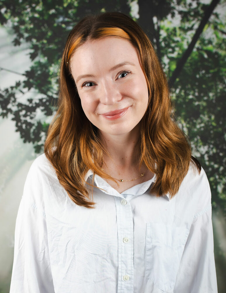 smiling young red headed white woman wearing long-sleeved white shirt