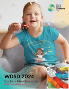 white, blonde-haired girl with Down syndrome blowing bubbles, wearing a turquoise t-shirt featuring an illustrated girl with Down syndrome