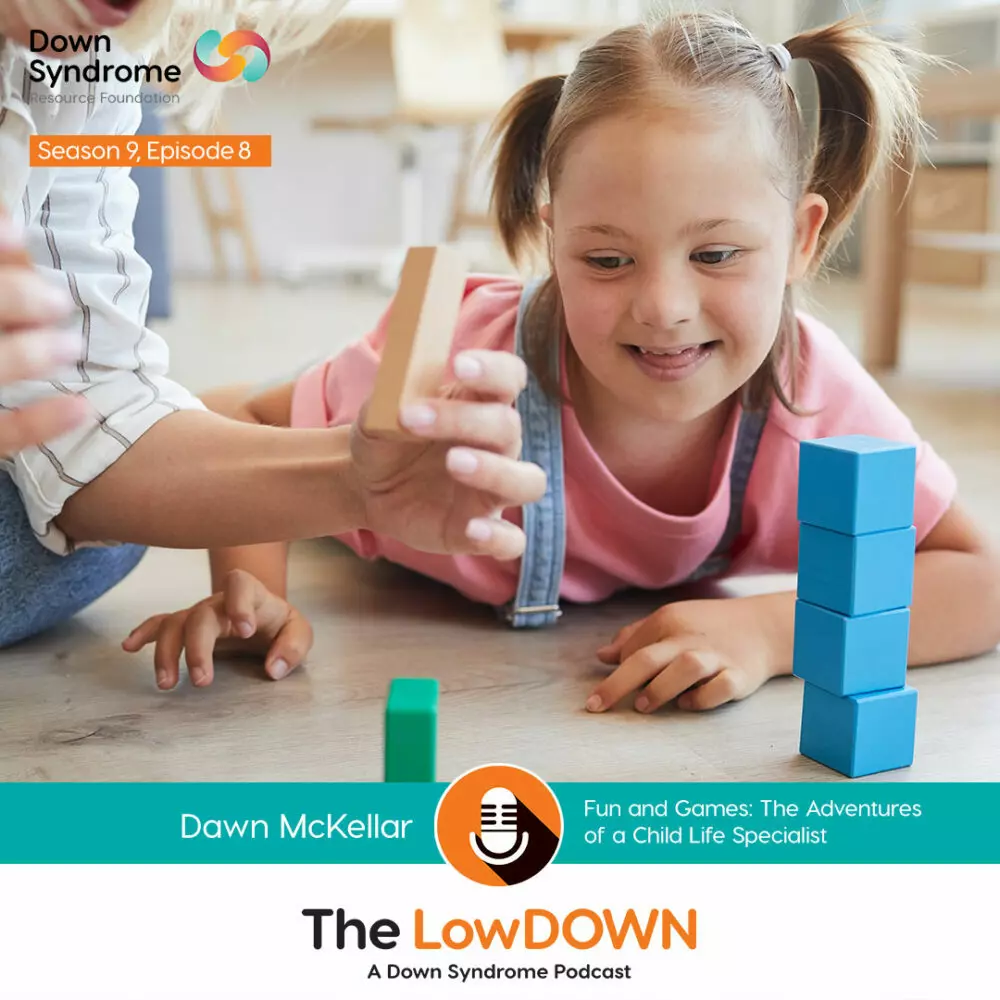 young white girl with Down syndrome lies on floor and stacks blocks